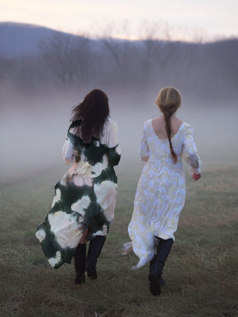 Deux femmes portant des robes imprimées Lexa Galbi, motifs floraux délicats, marchant dans un champ embrumé
